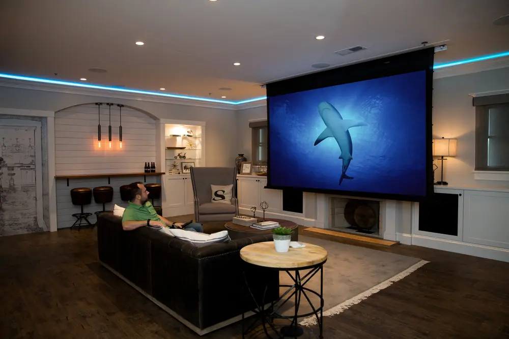 A man sitting in front of a large screen tv.