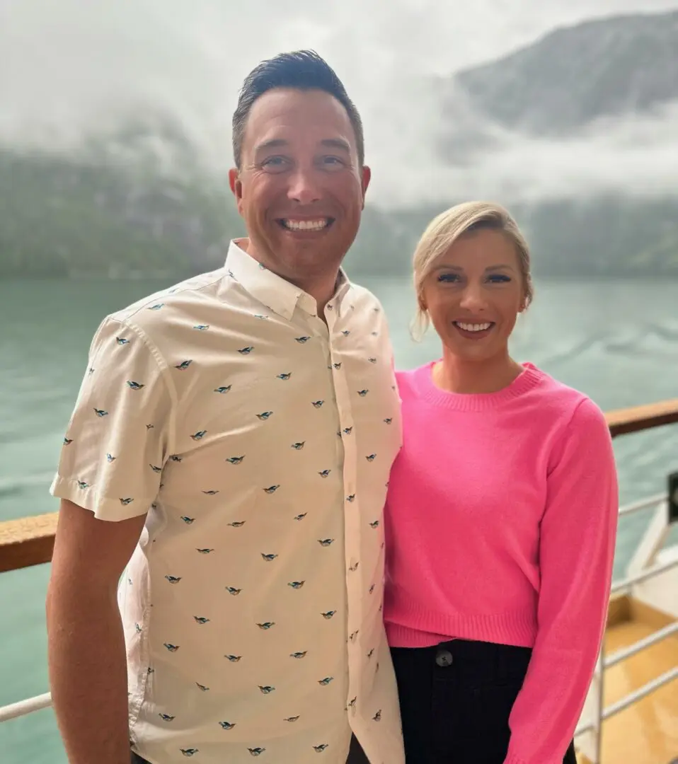 A man and woman standing on the deck of a boat.