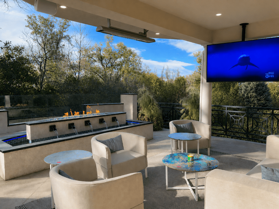 A backyard patio with seating, a modern fireplace, water features, and an outdoor TV.